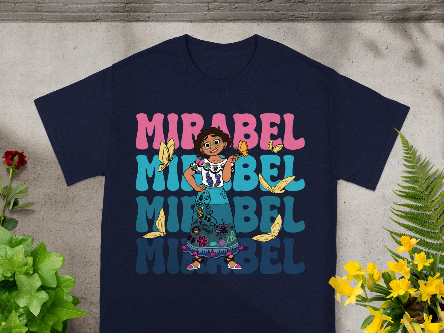 Mirabel from Encanto on a navy t-shirt with colorful "MIRABEL" text.