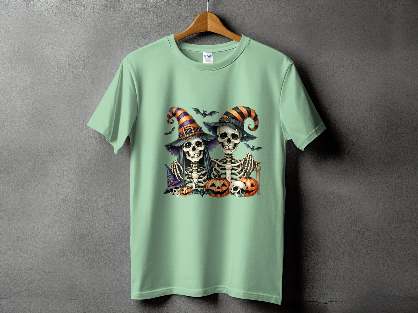 Mint green t-shirt with Halloween skeletons, pumpkins, and bats graphic print.