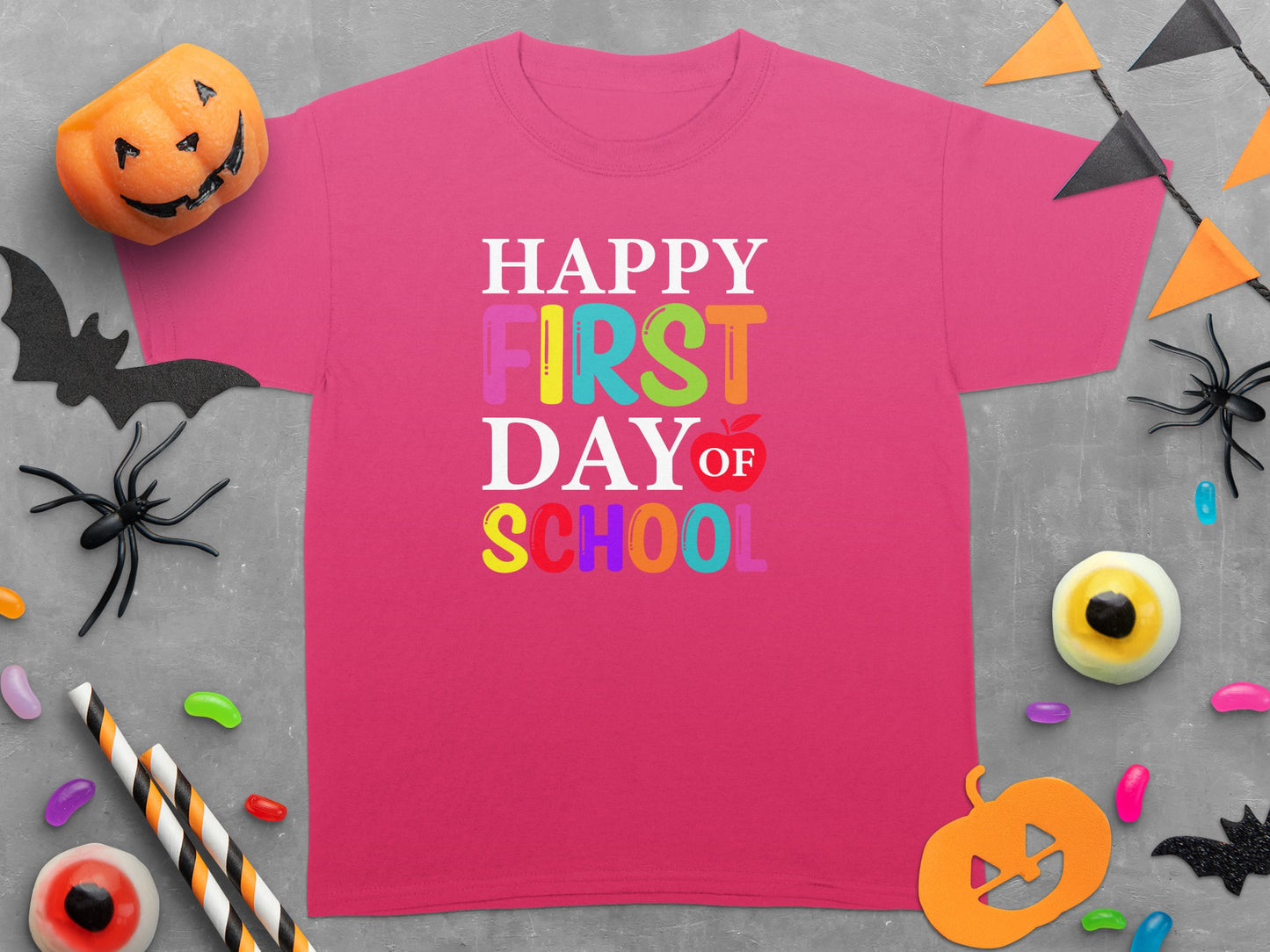 Pink t-shirt with "Happy First Day Of School" text and Halloween decorations.