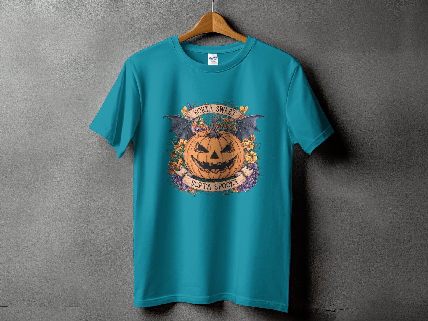 Teal t-shirt with Halloween graphic featuring a pumpkin, bats, flowers, and text.