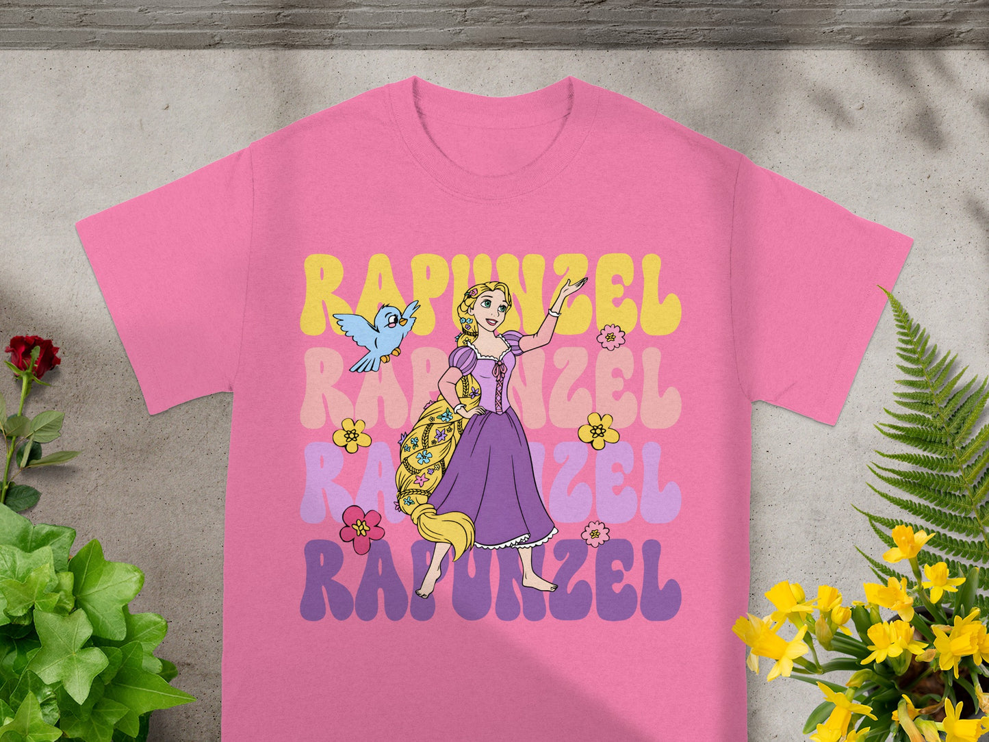 Rapunzel graphic tee with flowing hair, birds, and flowers on a pink shirt.