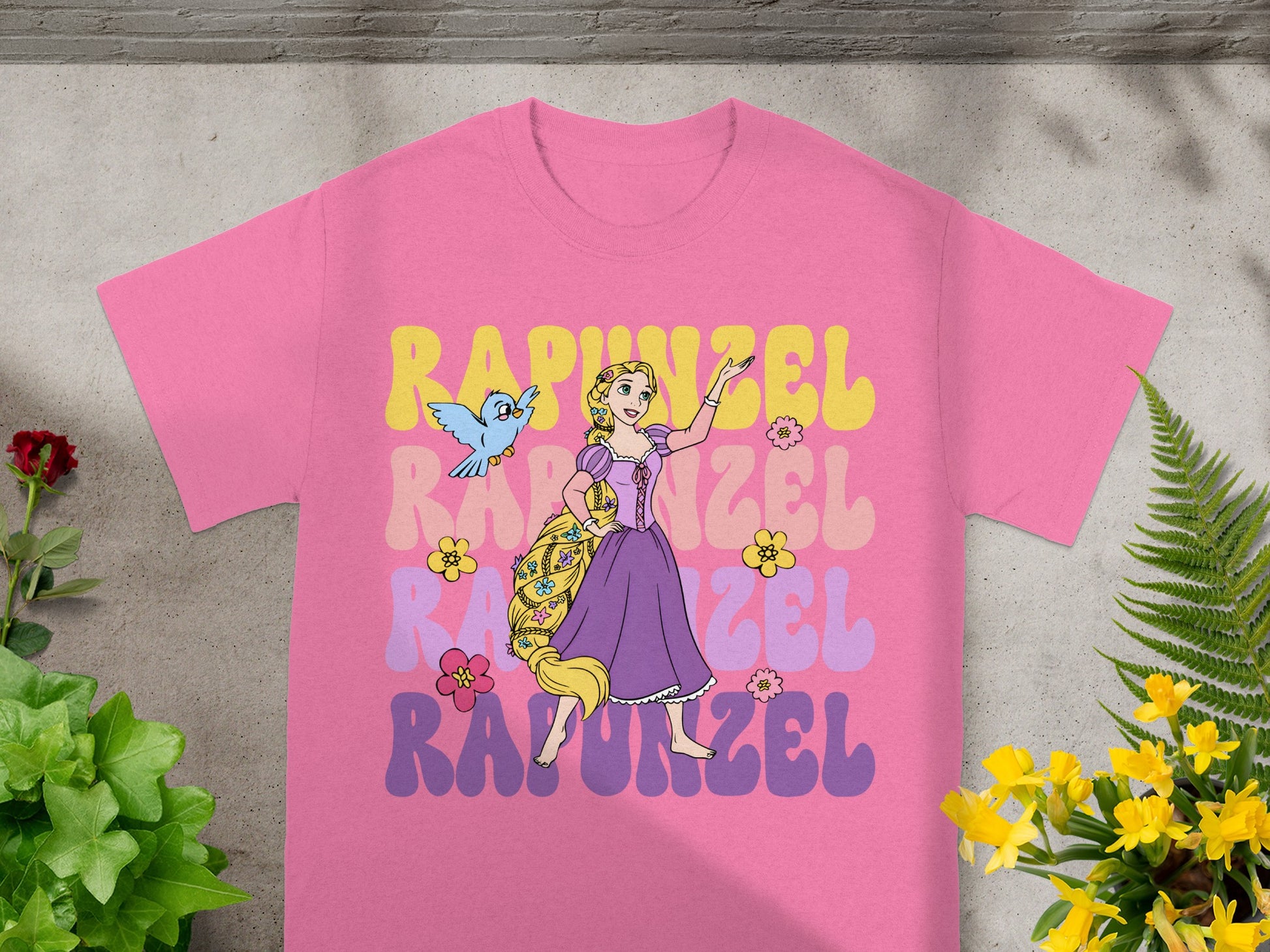 Rapunzel graphic tee with flowing hair, birds, and flowers on a pink shirt.