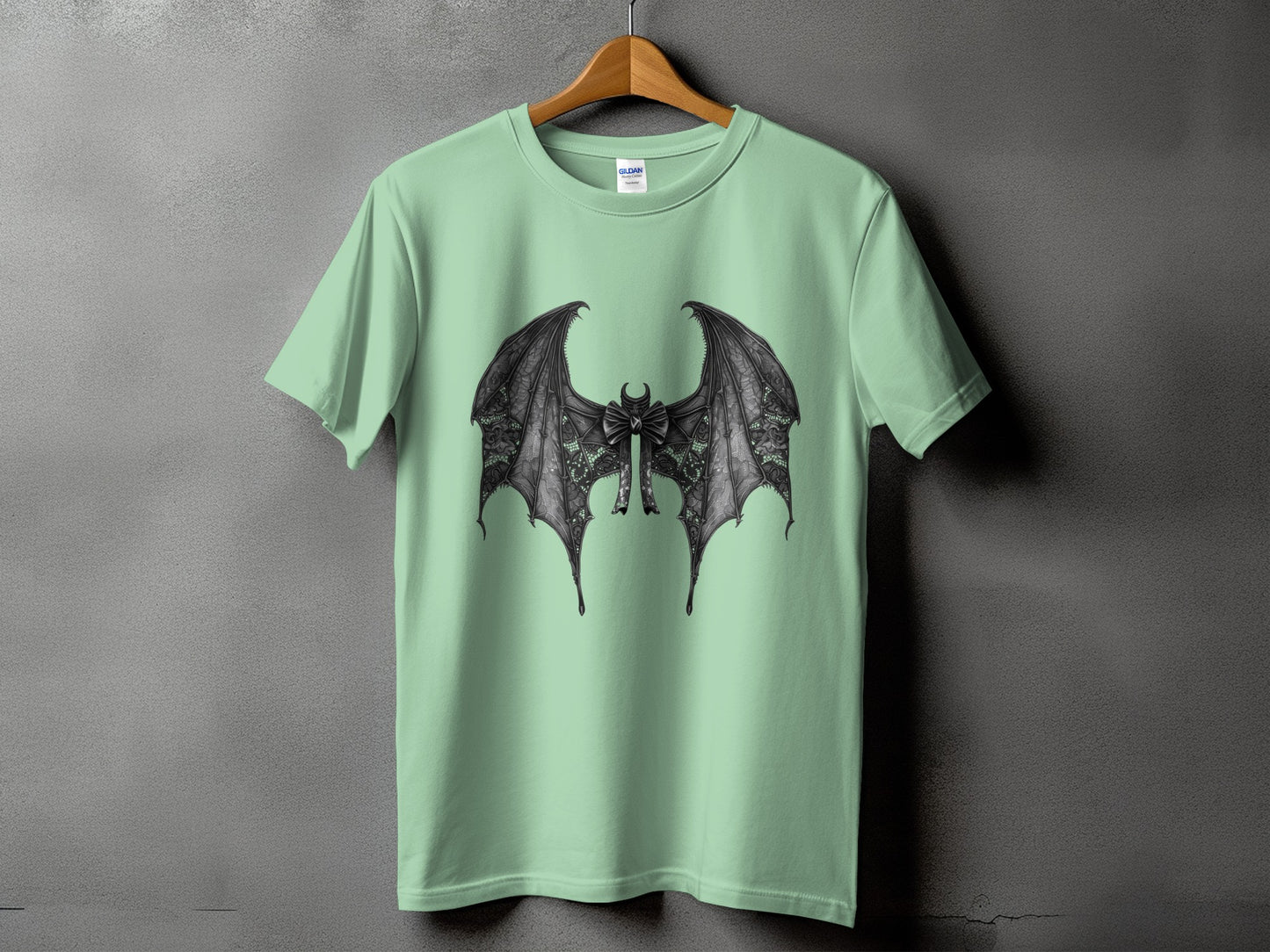 Light green t-shirt with a black bat wings and bow graphic on the front.