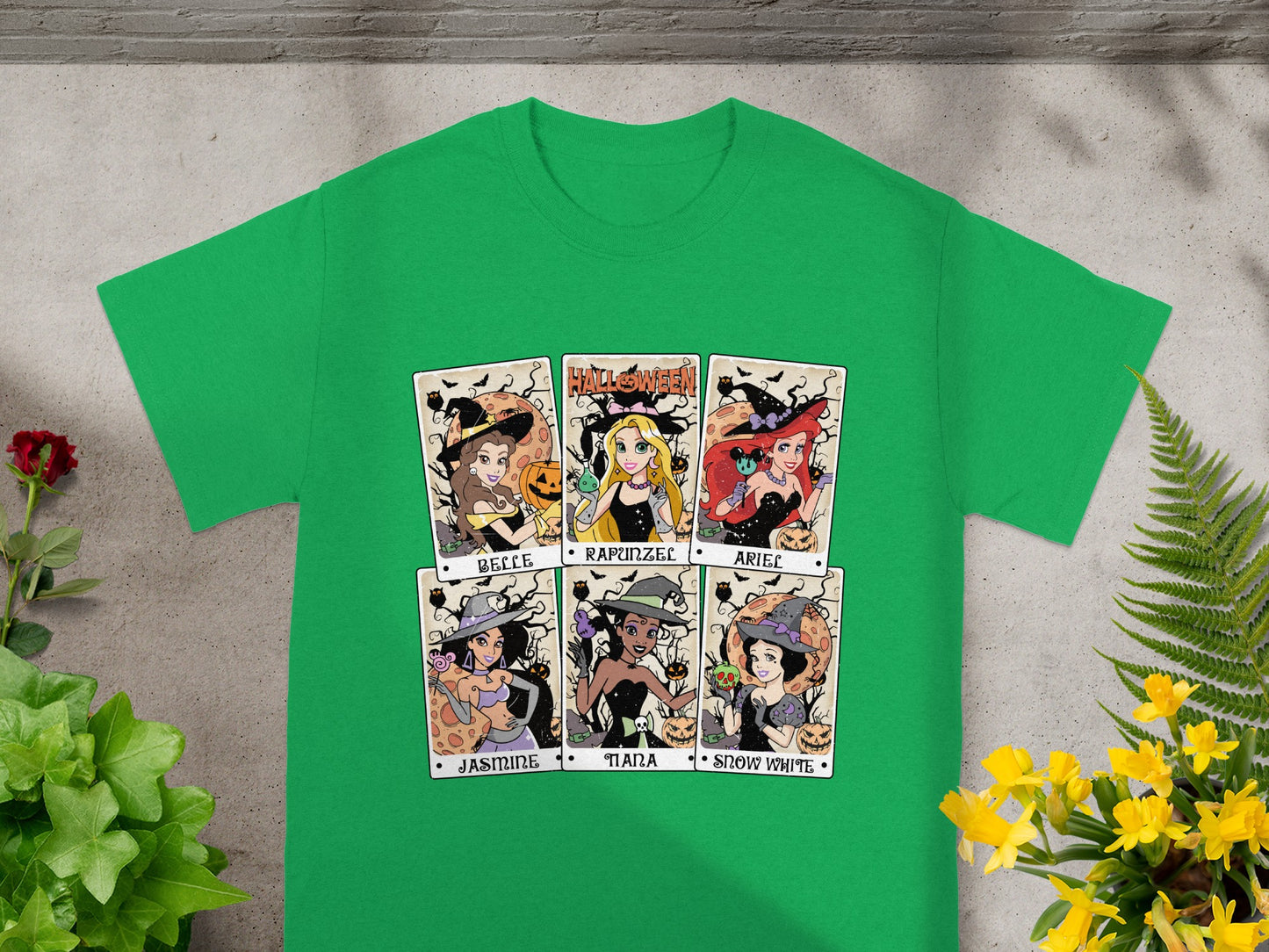 Green t-shirt with six Halloween-themed princess portraits: Belle, Rapunzel, Ariel, Jasmine, Tiana, Snow White.