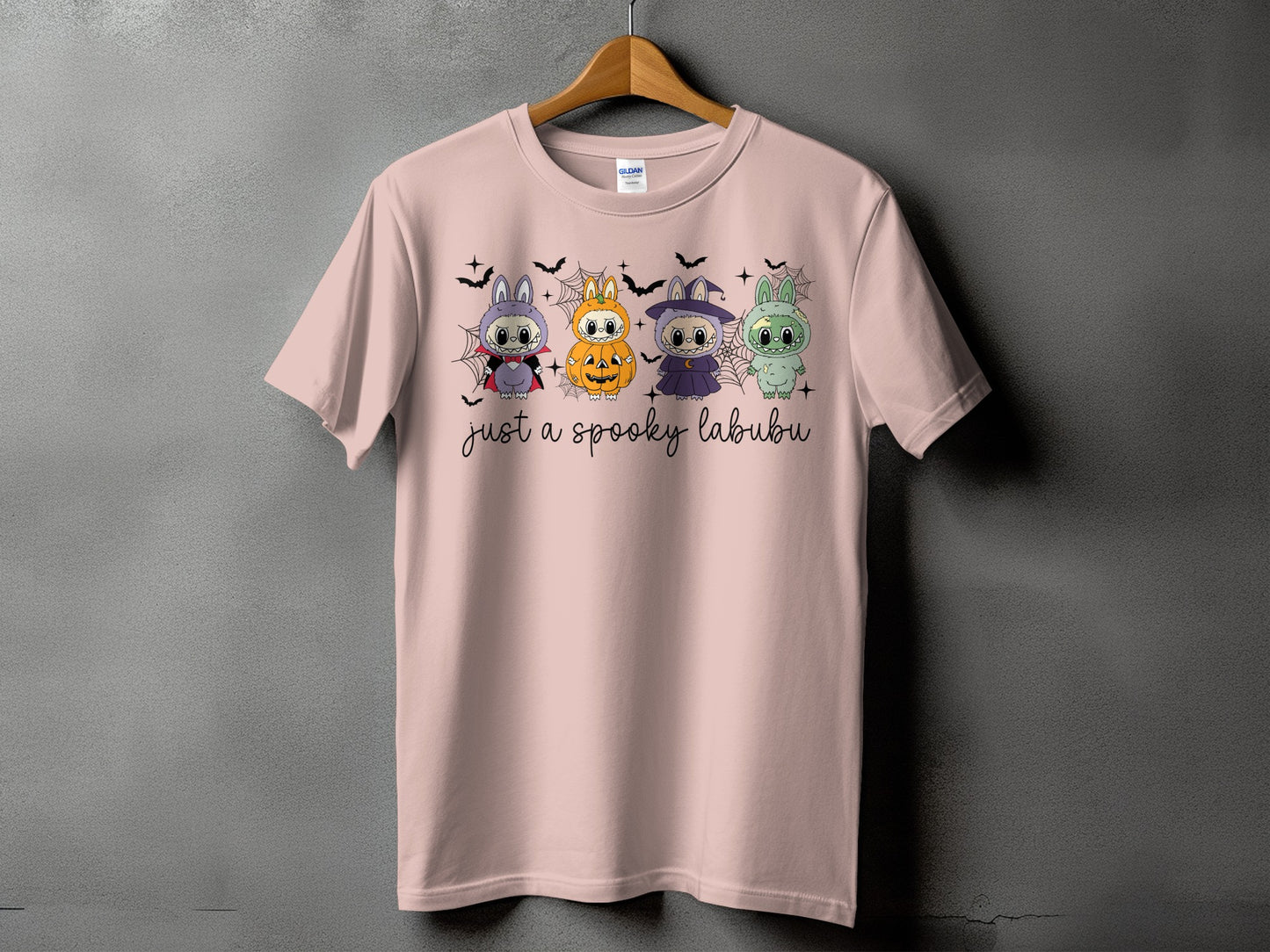 Pink t-shirt with four Halloween-themed cartoon creatures and "just a spooky labubu" text.
