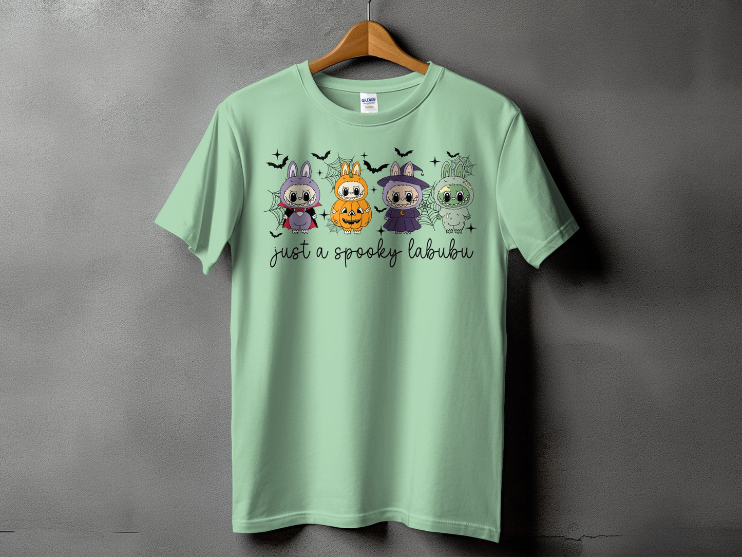 Light green t-shirt with four Halloween-themed Labubu characters and "just a spooky labubu" text.