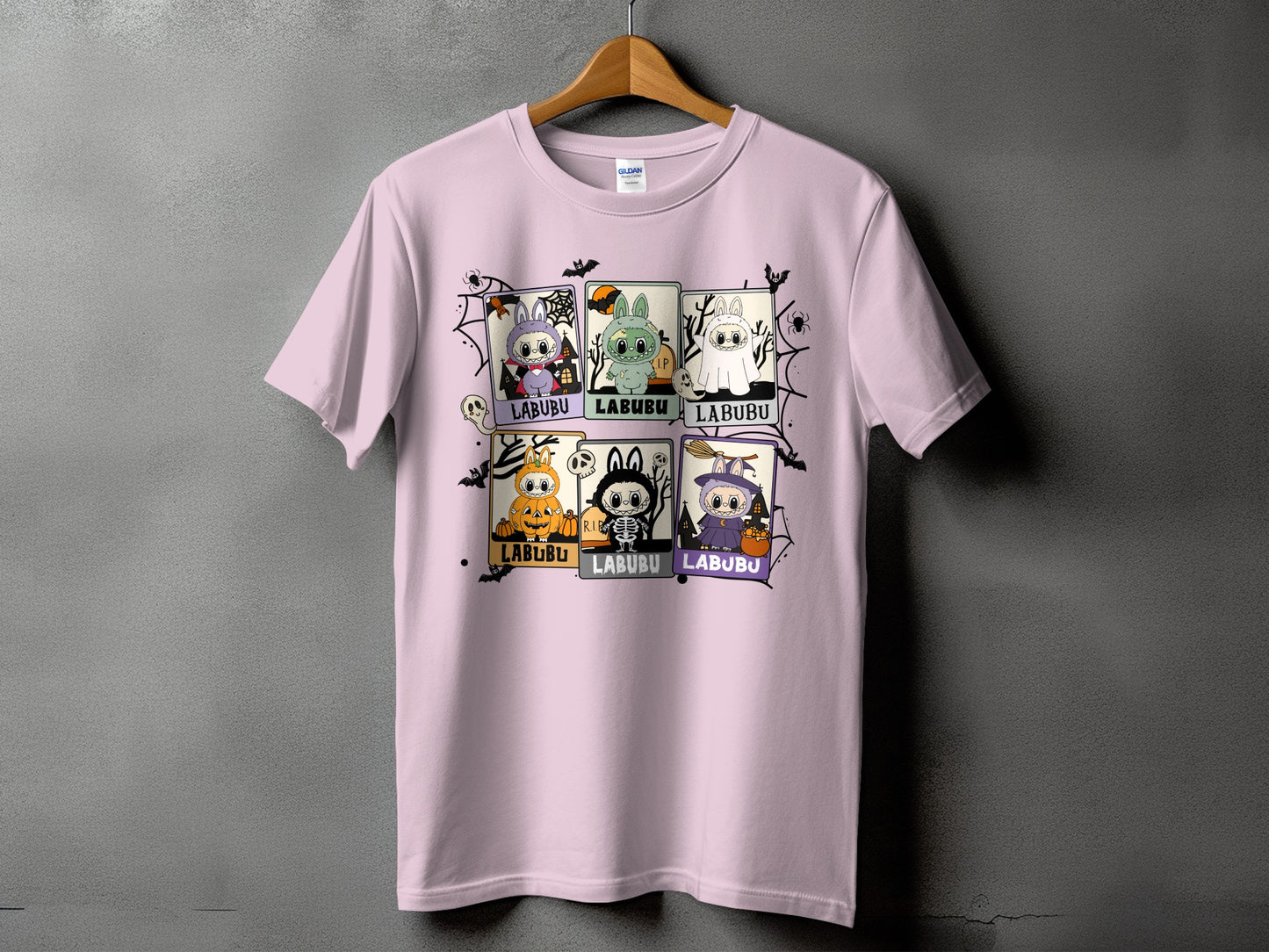 Pink t-shirt with six Halloween-themed Labubu character illustrations and spiderweb graphics.