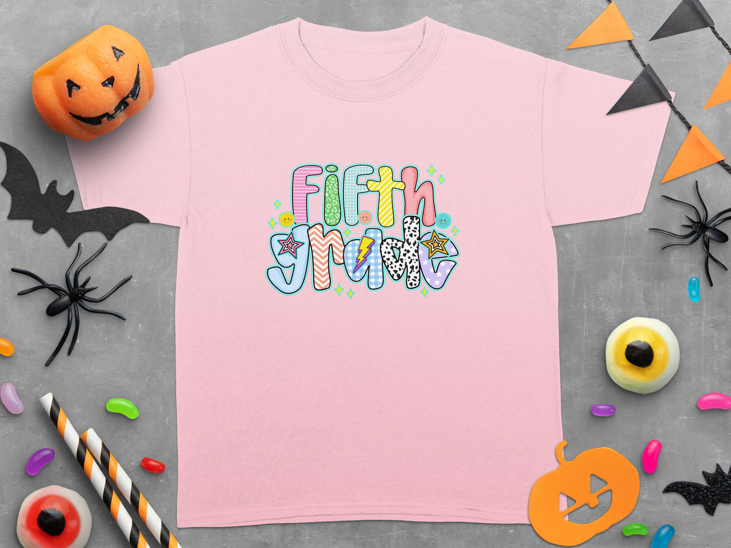 Pink t-shirt with "Fifth Gradv" graphic and Halloween decorations.