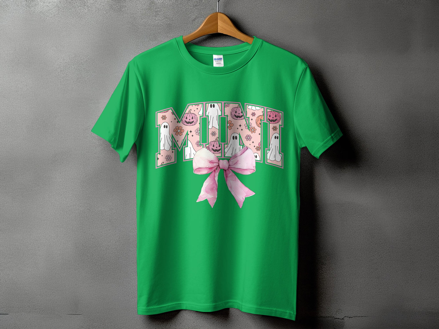 Green t-shirt with "MIMI" in Halloween-themed letters and a pink bow.