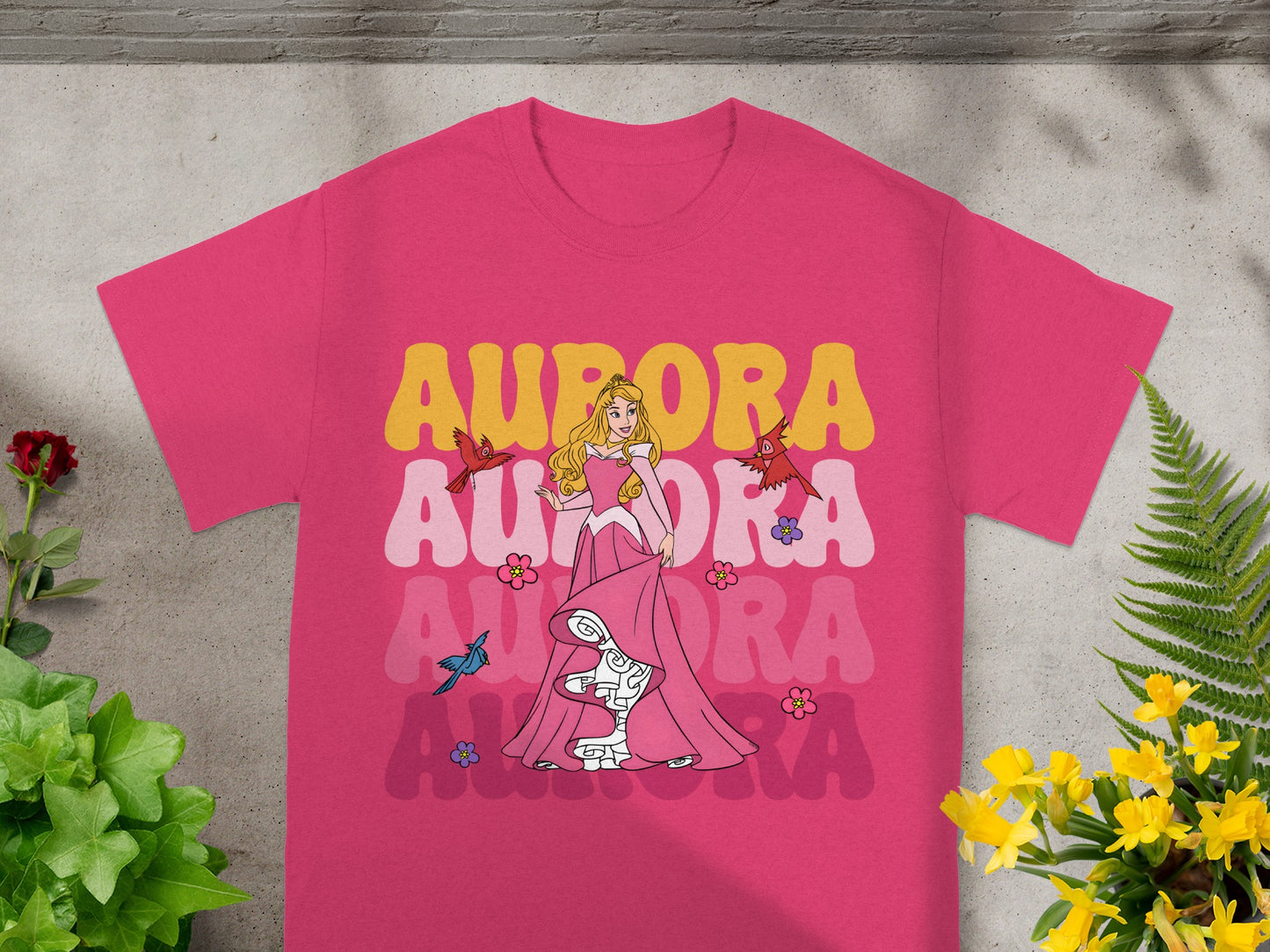 Aurora in pink dress with colorful "Aurora" text on a pink t-shirt.