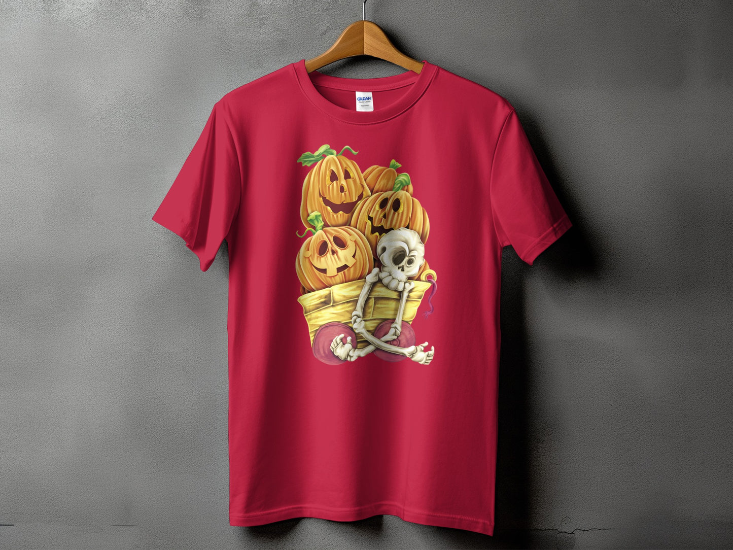 Skeleton and pumpkins in a wagon Halloween graphic on a red t-shirt.