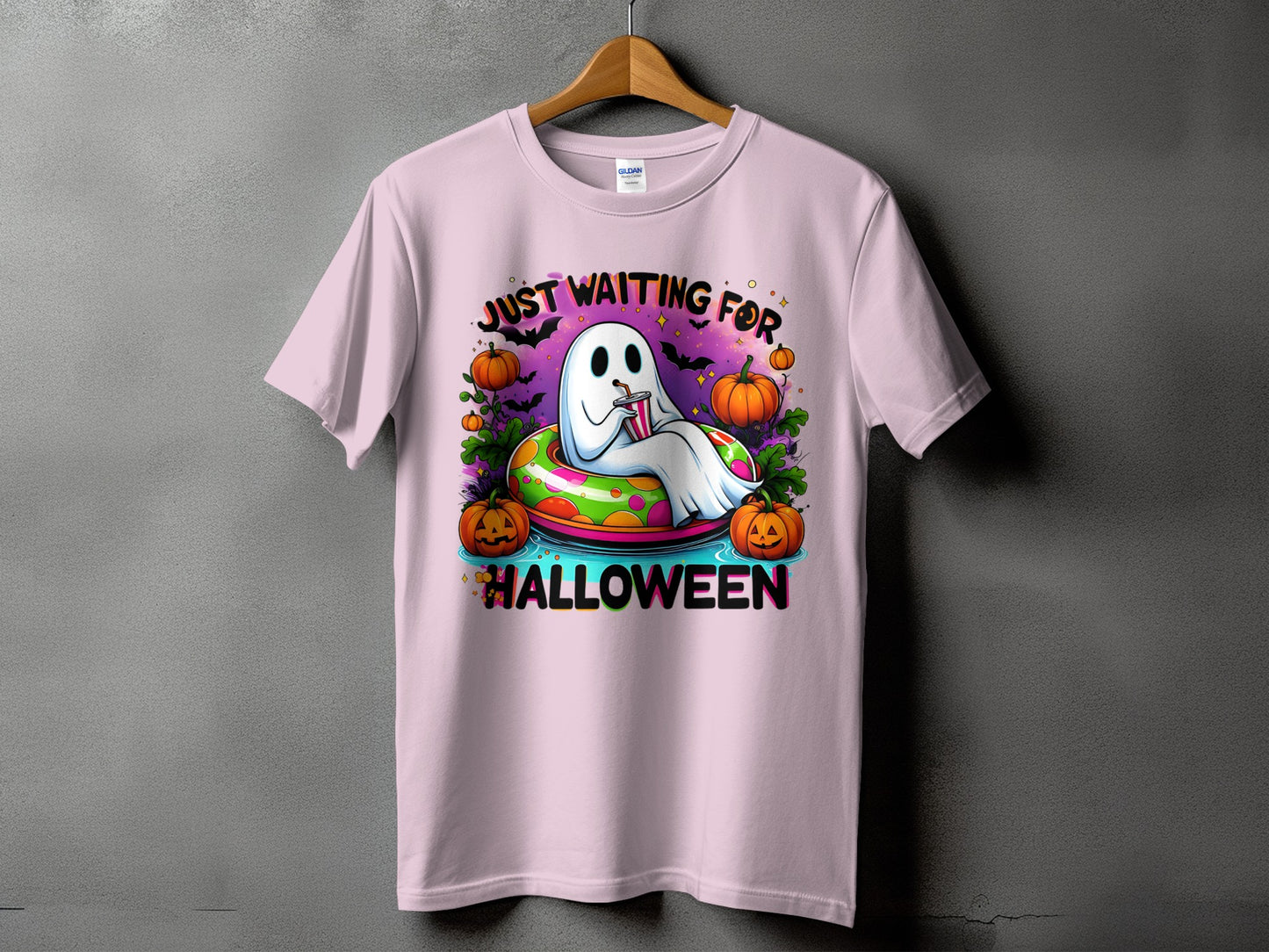 Pink t-shirt with a cartoon ghost in a pool ring saying "Just Waiting For Halloween."