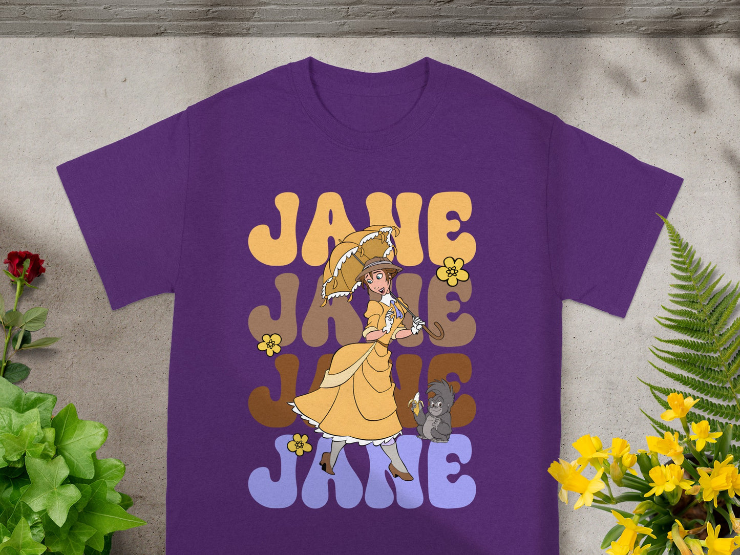 Purple t-shirt with "JANE" in large, stacked, yellow lettering and a woman with a parasol.