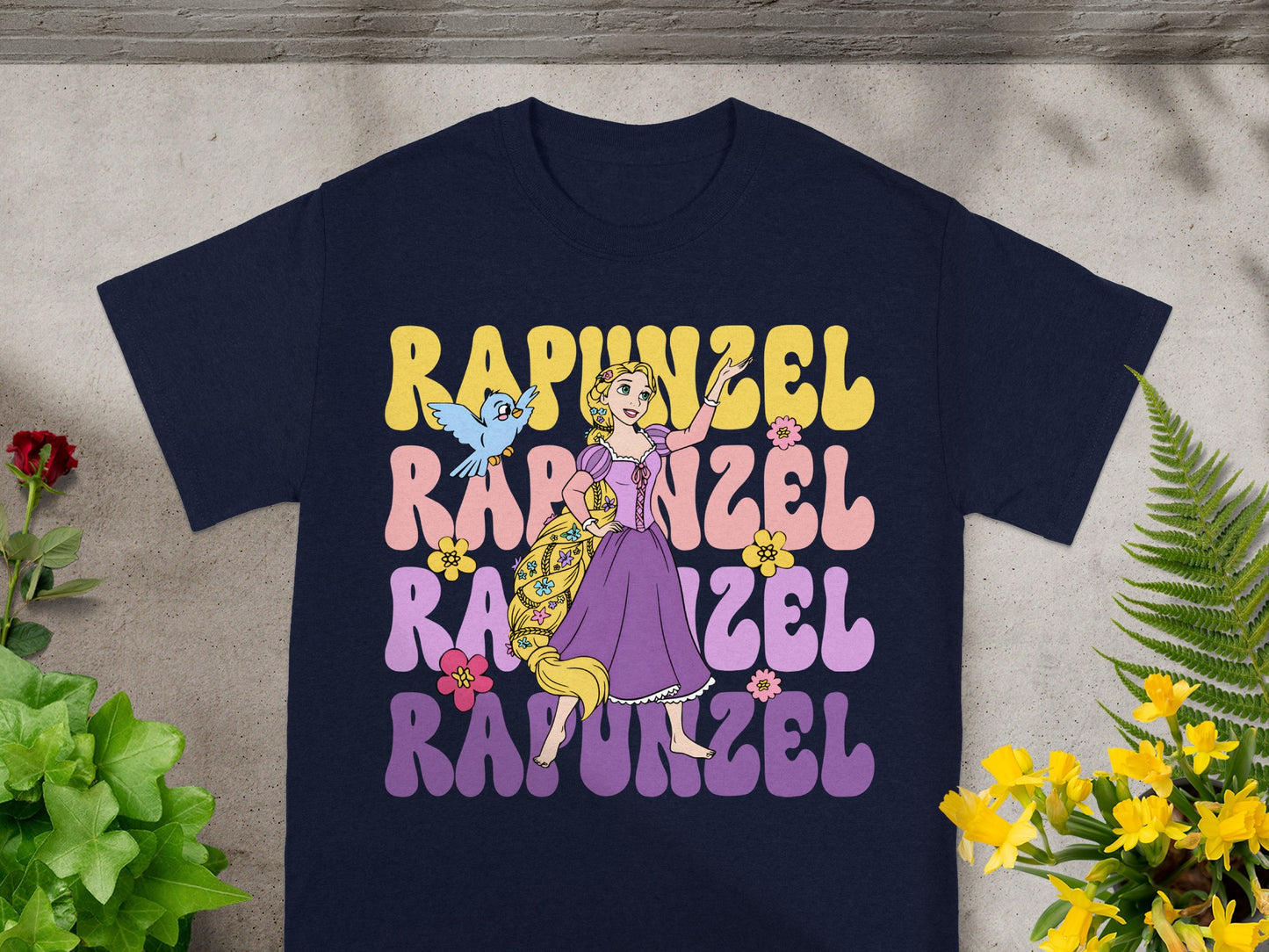 Rapunzel graphic on a navy t-shirt with purple, pink, and yellow text.