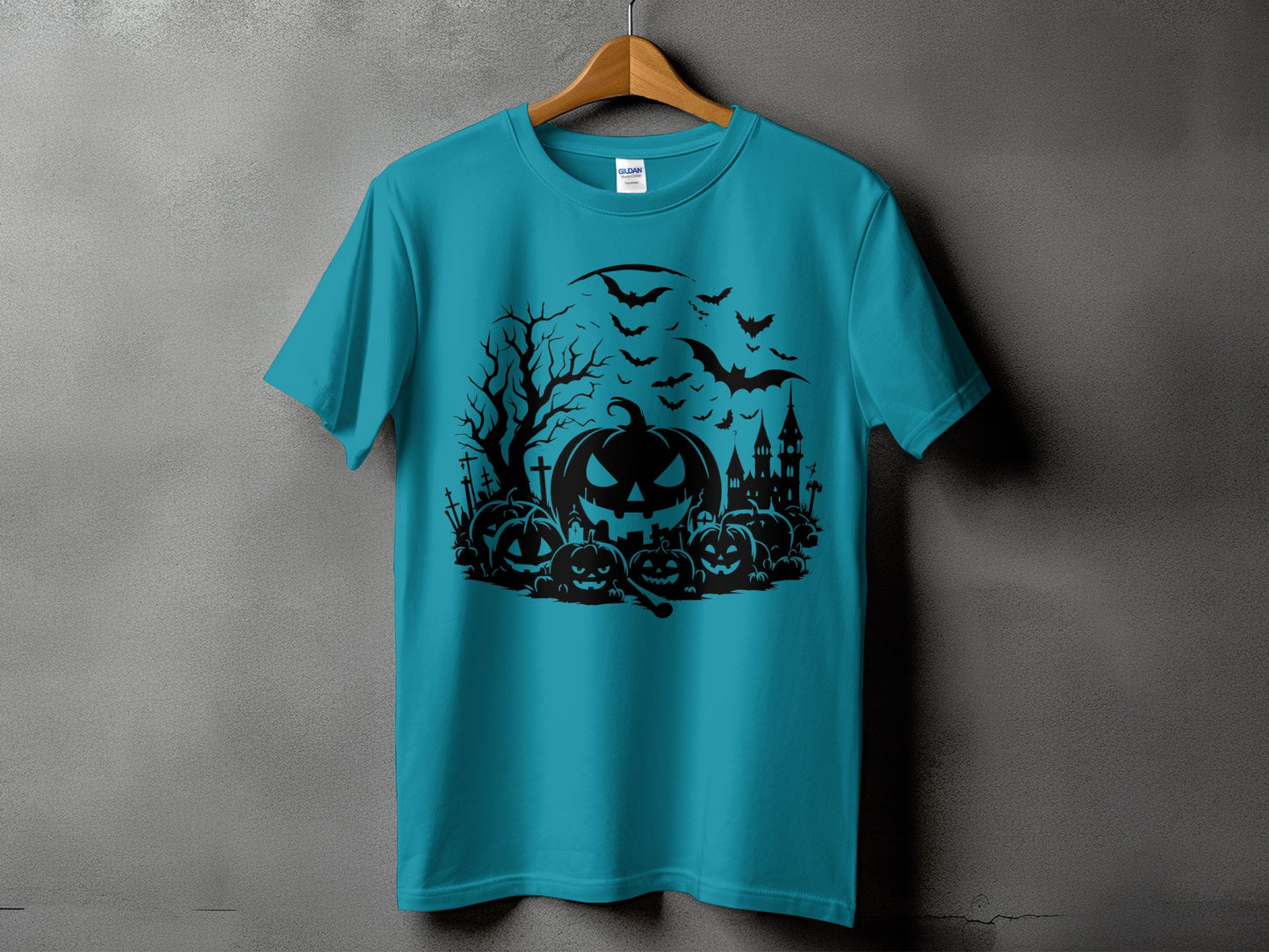 Teal t-shirt with black Halloween graphic of pumpkins, bats, haunted house, and tree.