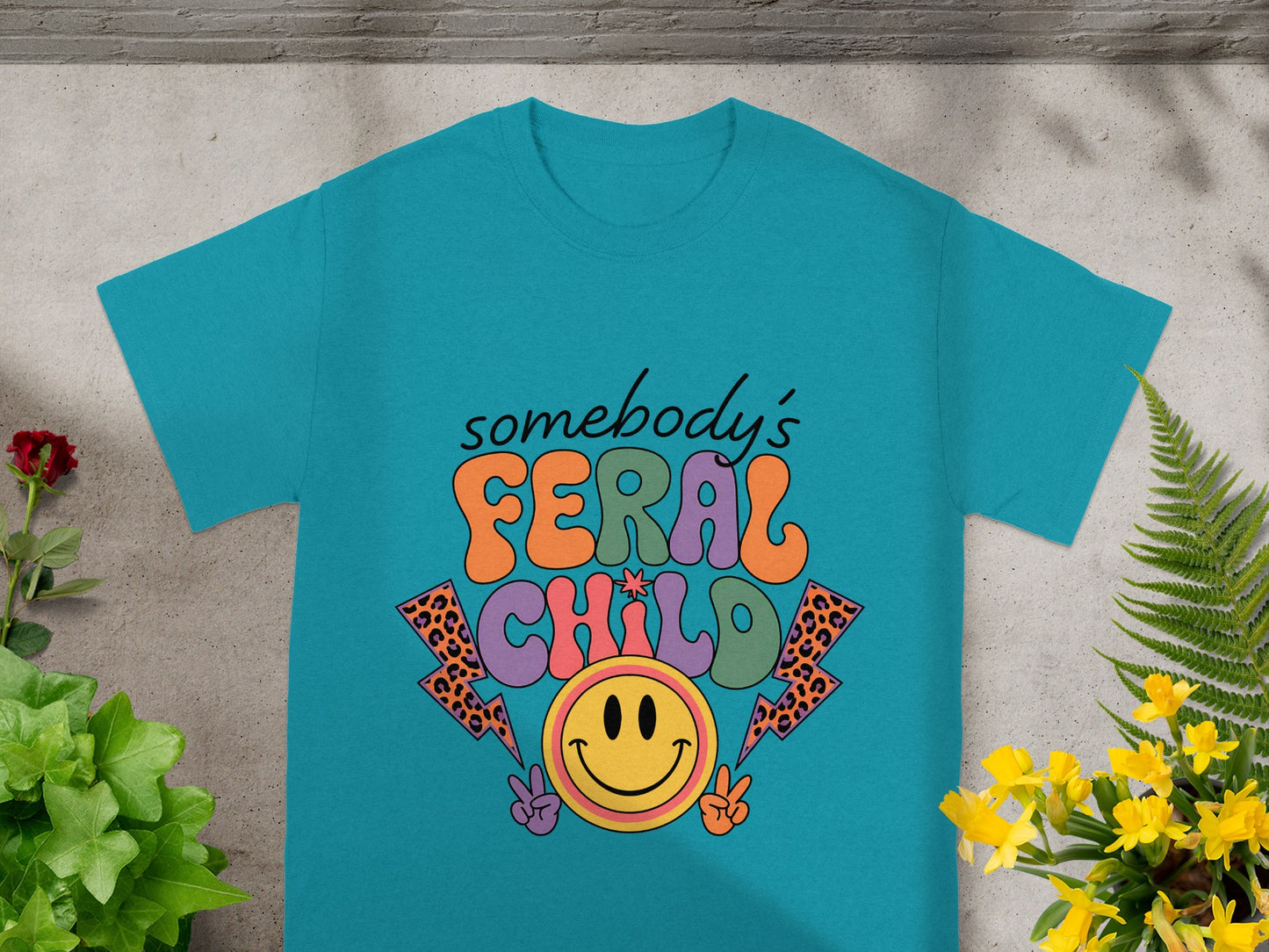 Teal t-shirt with groovy text "somebody's FERAL CHILD" and a smiley face.