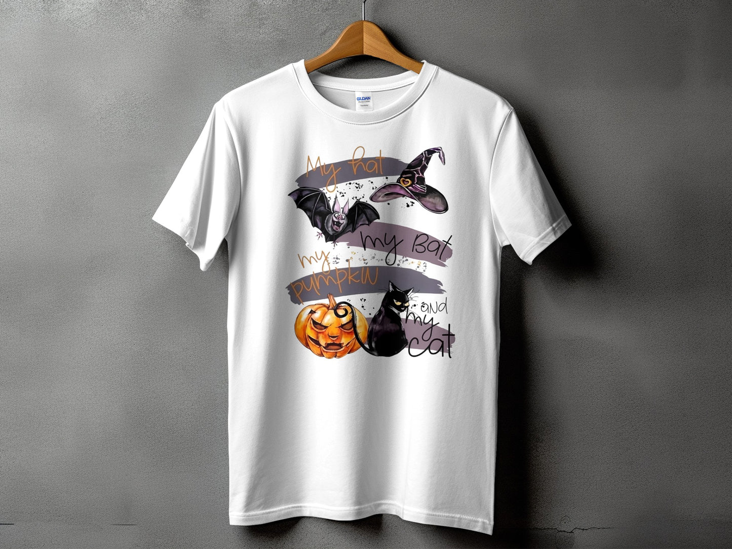 White t-shirt with Halloween graphic: bat, witch hat, pumpkin, black cat, and text.