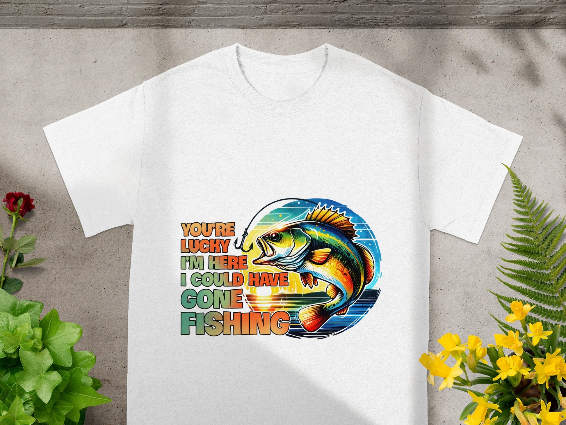 White t-shirt with colorful graphic of a fish being reeled in and text: You're Lucky I'm Here I Could Have Gone Fishing.
