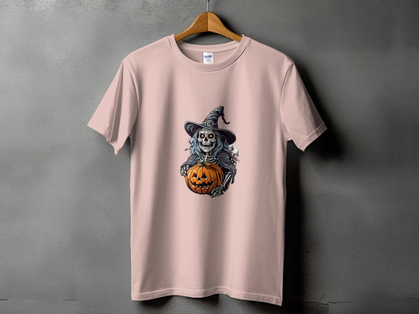 Skeleton in witch hat holds carved pumpkin on a pink t-shirt.