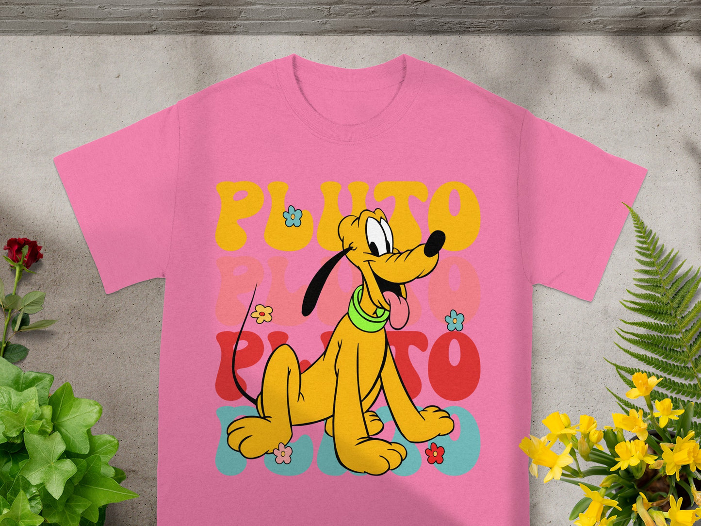Pink t-shirt with a colorful, retro Pluto graphic and flowers.