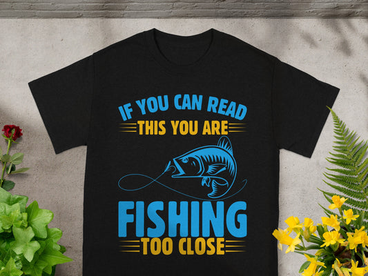 Black t-shirt with blue and yellow text saying "IF YOU CAN READ THIS YOU ARE FISHING TOO CLOSE".