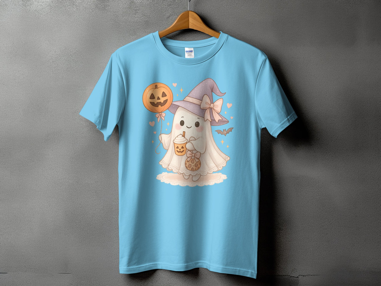 Light blue t-shirt with a cartoon ghost wearing a witch hat and holding a pumpkin balloon.