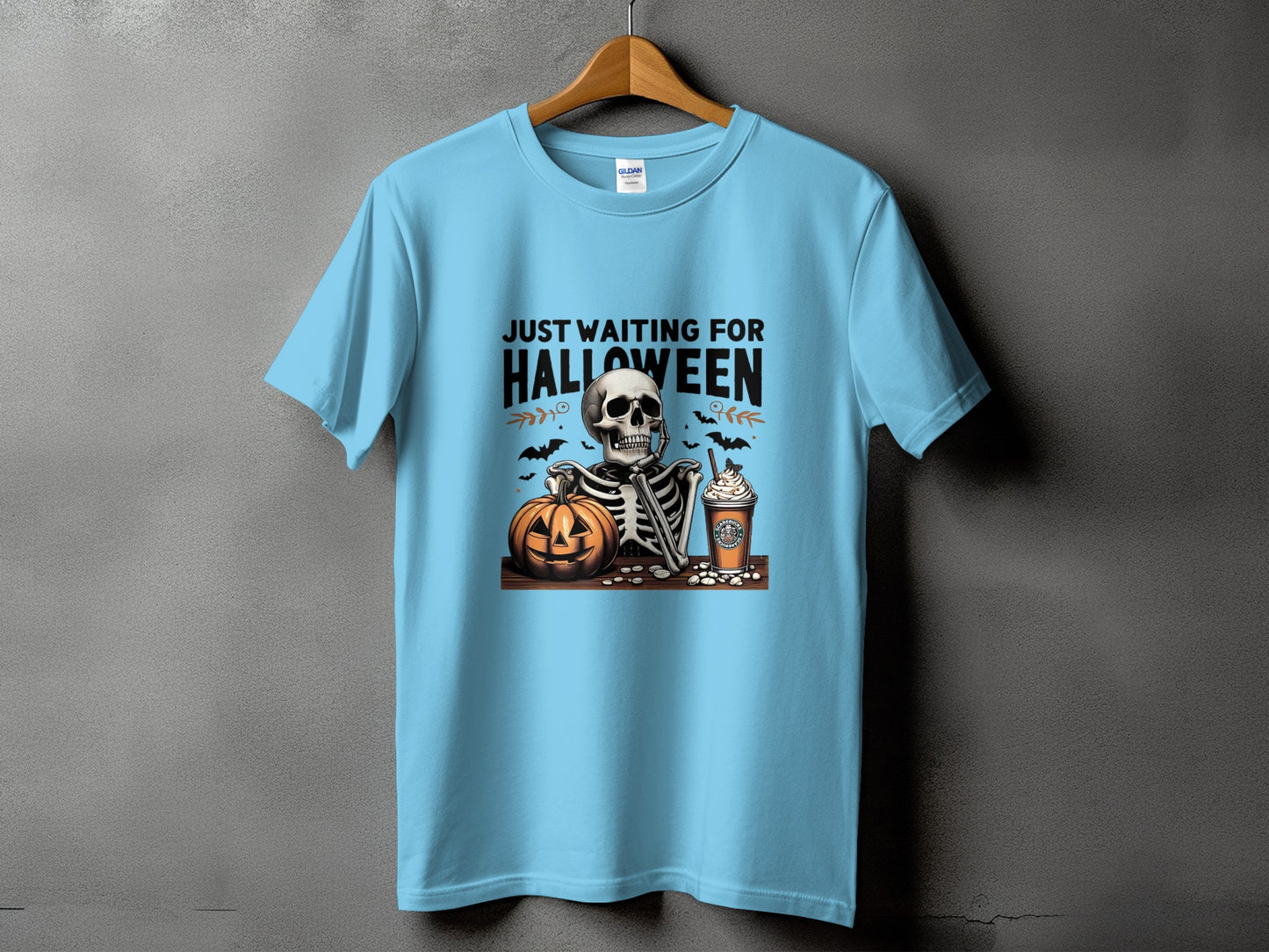 Light blue t-shirt with a skeleton, pumpkin, coffee, and text reading "JUST WAITING FOR HALLOWEEN".
