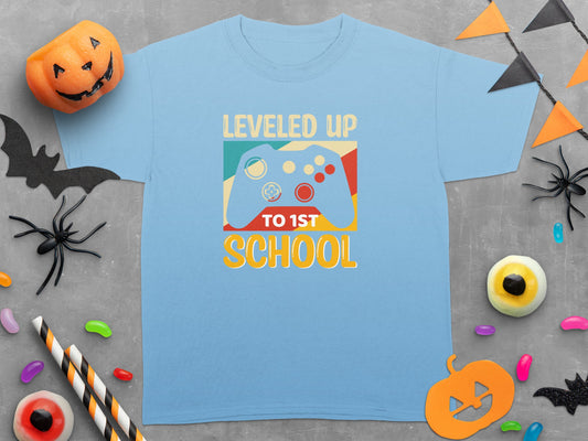 Light blue t-shirt with "Leveled Up to 1st School" and video game controller graphic.