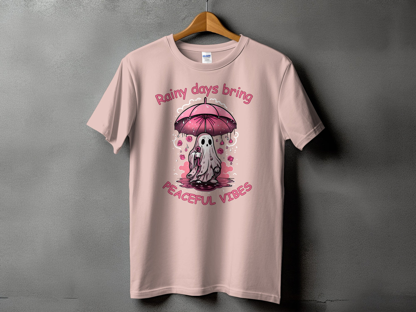Pink t-shirt with a ghost holding an umbrella with "Rainy days bring peaceful vibes" text.