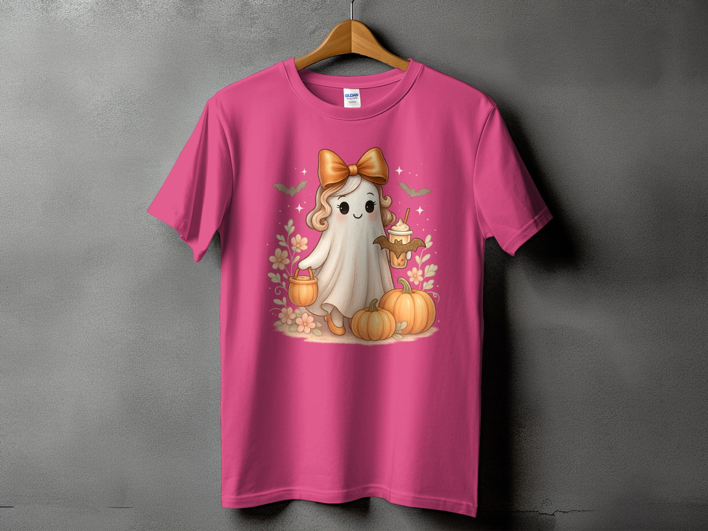 Pink t-shirt with a cute ghost holding a drink, surrounded by pumpkins and flowers.