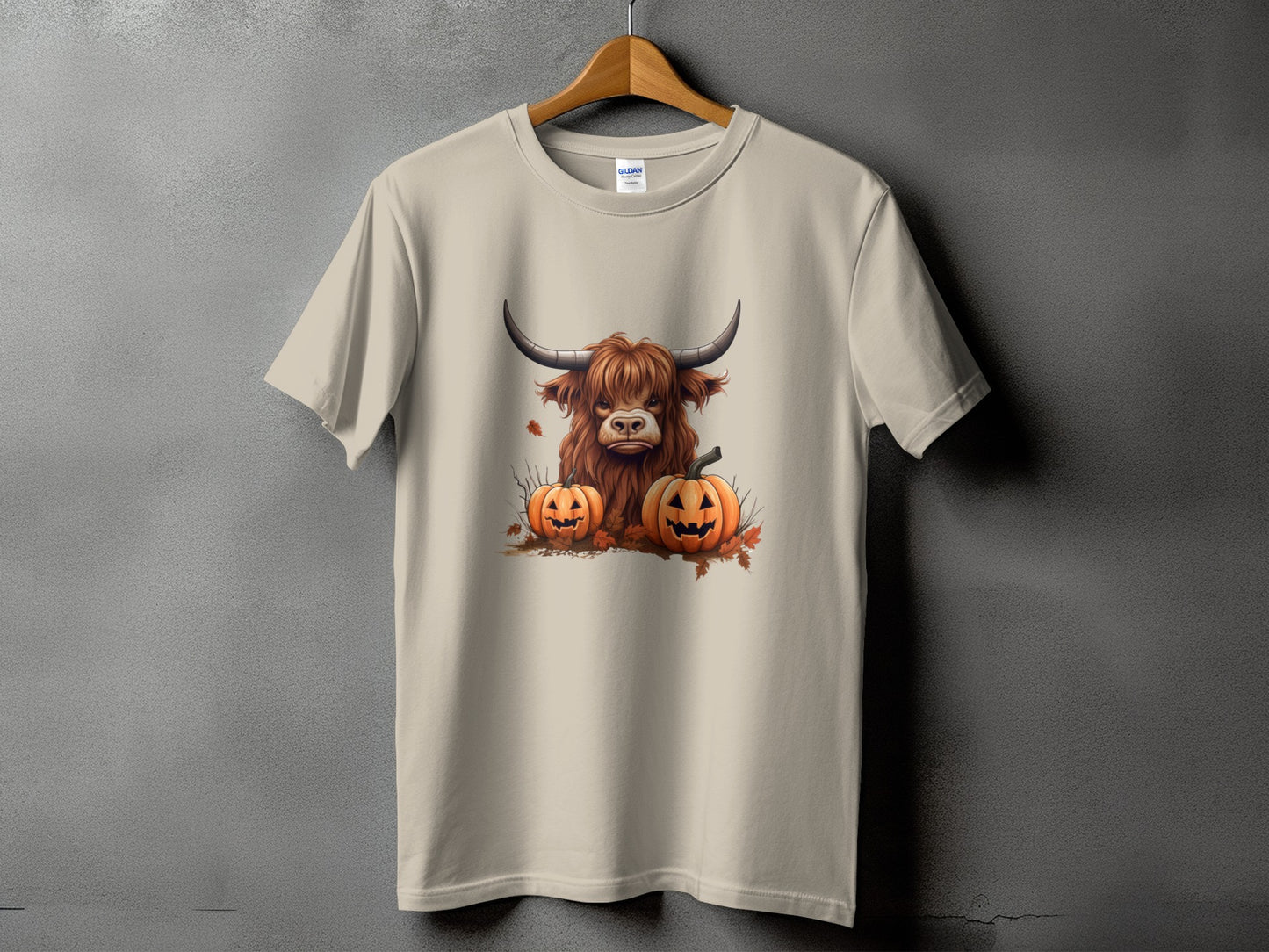 Tan t-shirt with a graphic of a Highland cow and two jack-o'-lanterns.