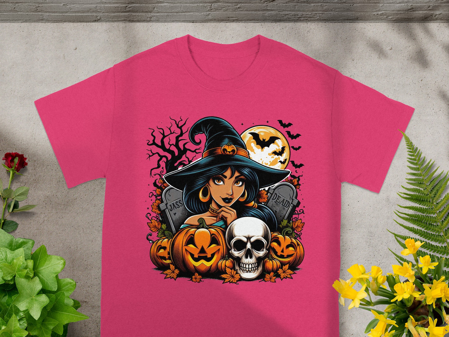 Pink t-shirt with Halloween graphic featuring witch, pumpkins, skull, tombstones, and bats.