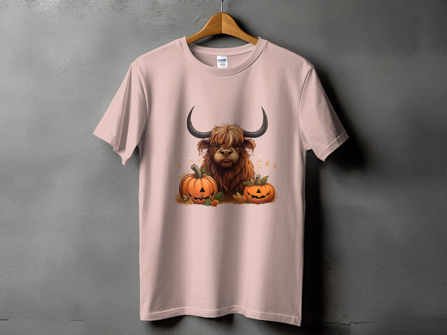 Highland cow with pumpkins and fall leaves graphic on a pink t-shirt.