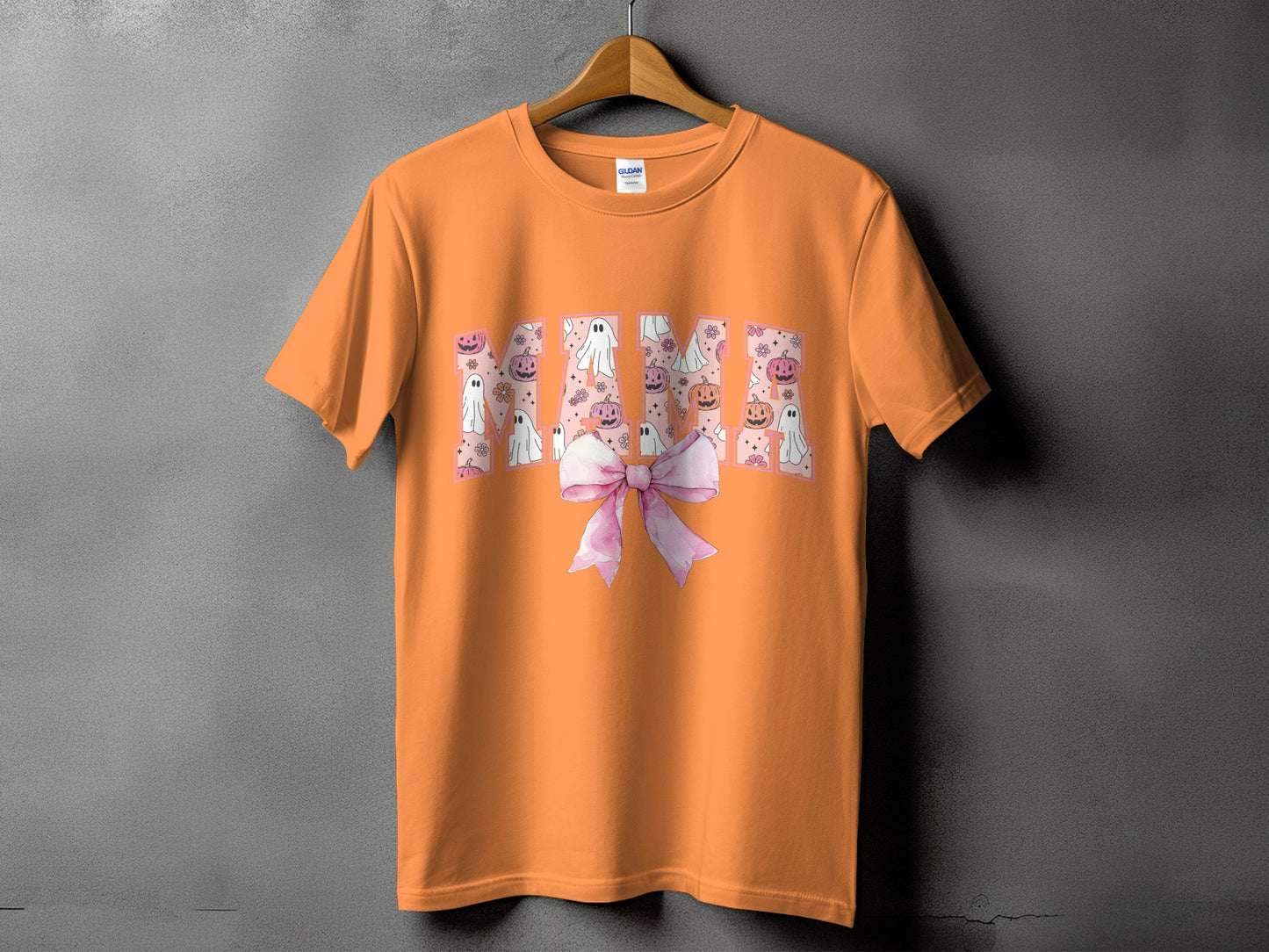 Orange t-shirt with "MAMA" graphic in Halloween themed font with ghosts and pumpkins.
