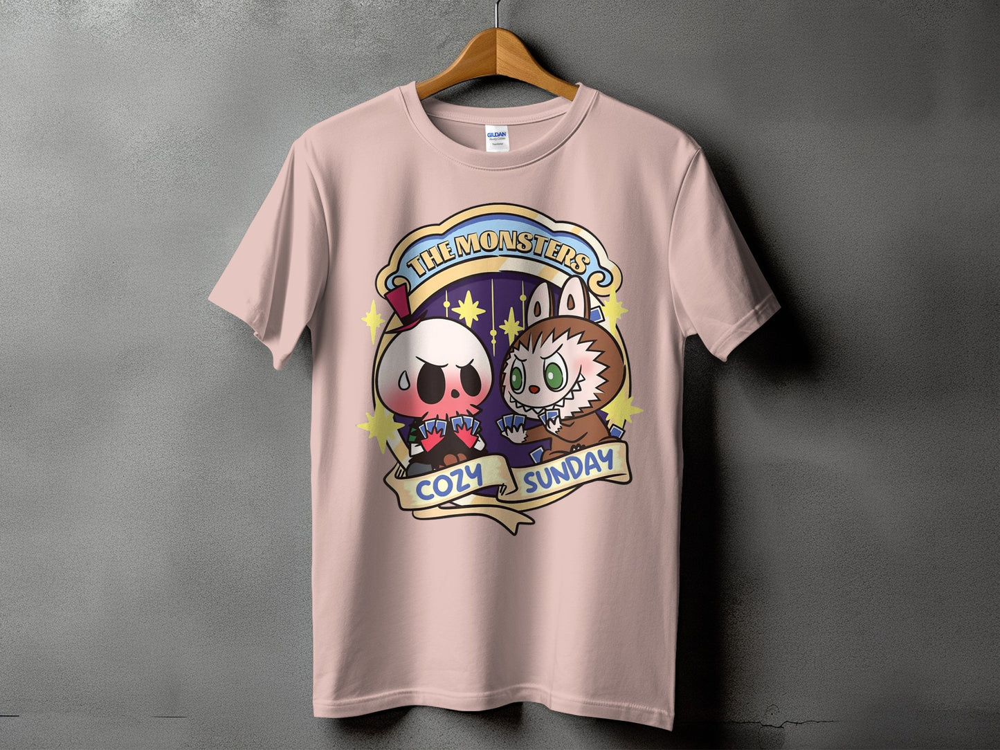 Pink t-shirt with a cartoon skull and monster playing cards, text reads "The Monsters Cozy Sunday".