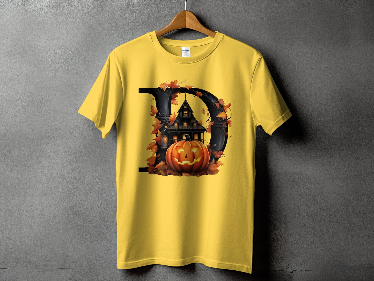 Yellow t-shirt with a black letter D graphic featuring a haunted house and jack-o'-lantern.