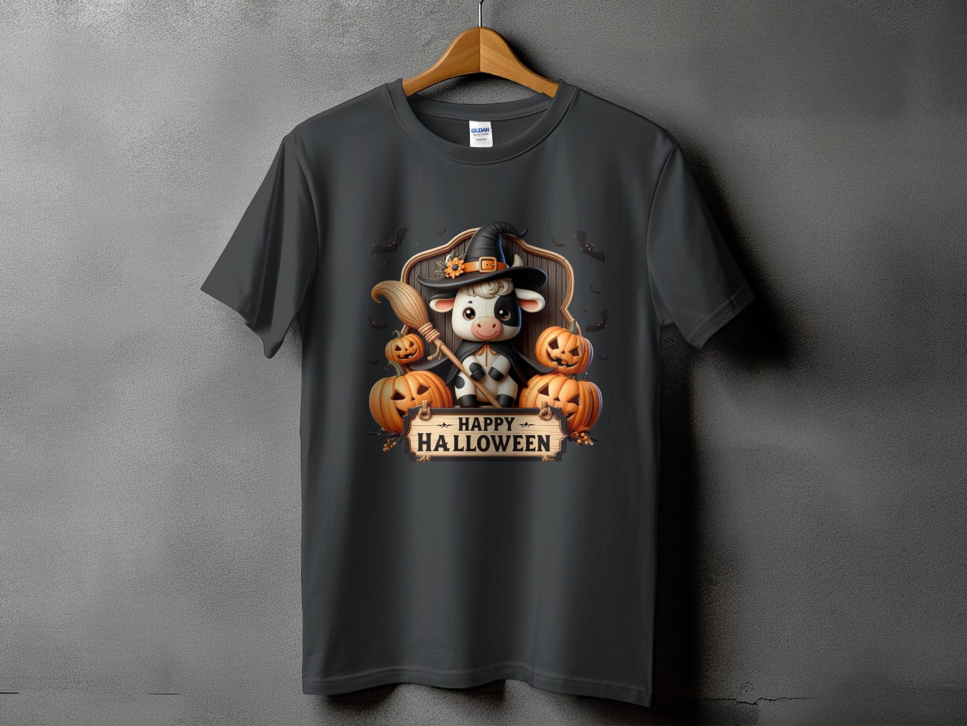 Dark t-shirt with a cartoon cow in a witch hat and bats with "Happy Halloween" text.