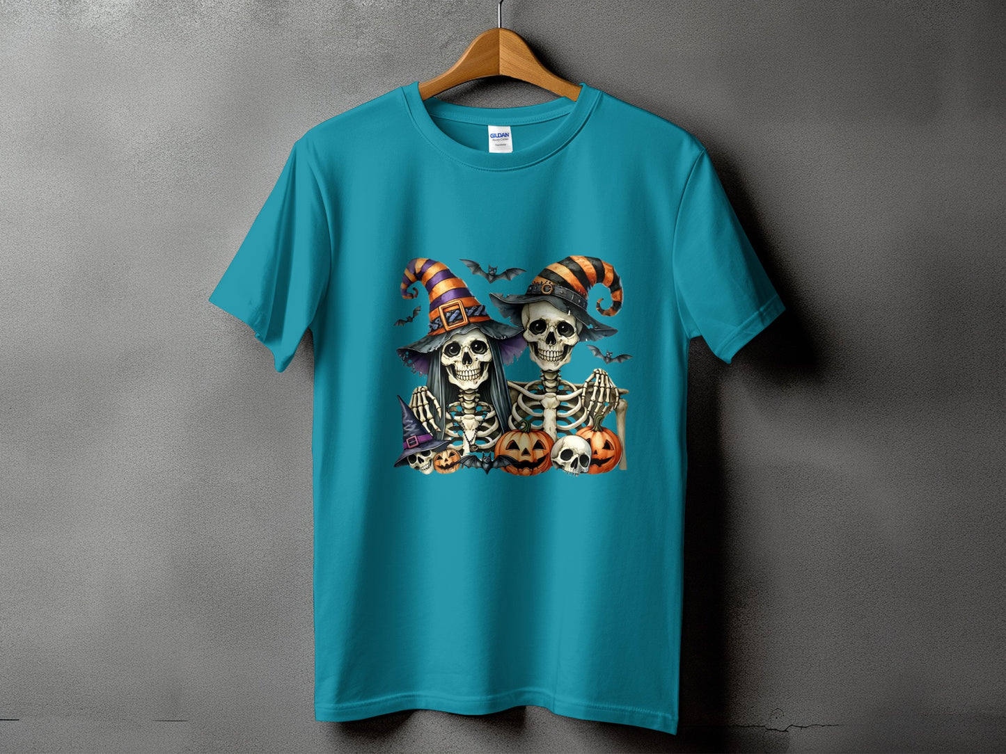 Teal t-shirt with Halloween skeletons, pumpkins, bats, and witch hats graphic.