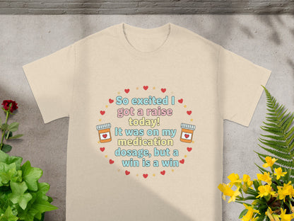 Cream t-shirt with "So excited I got a raise today! It was on my medication dosage, but a win is a win" text.
