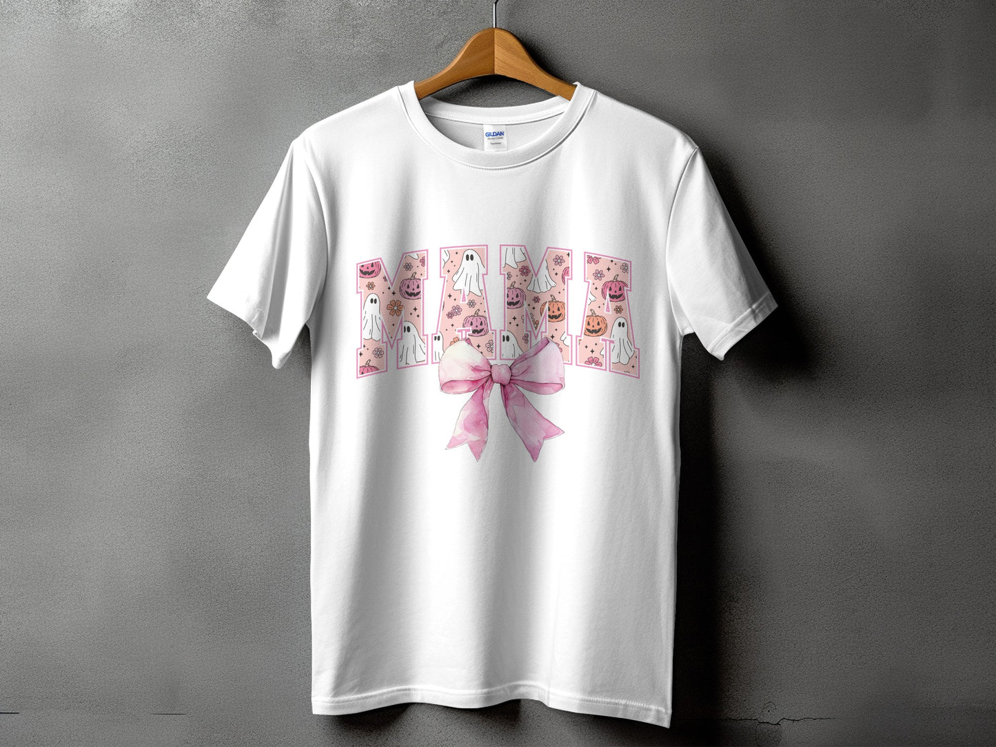 White t-shirt with "Mama" text featuring ghosts, pumpkins, and a pink bow.