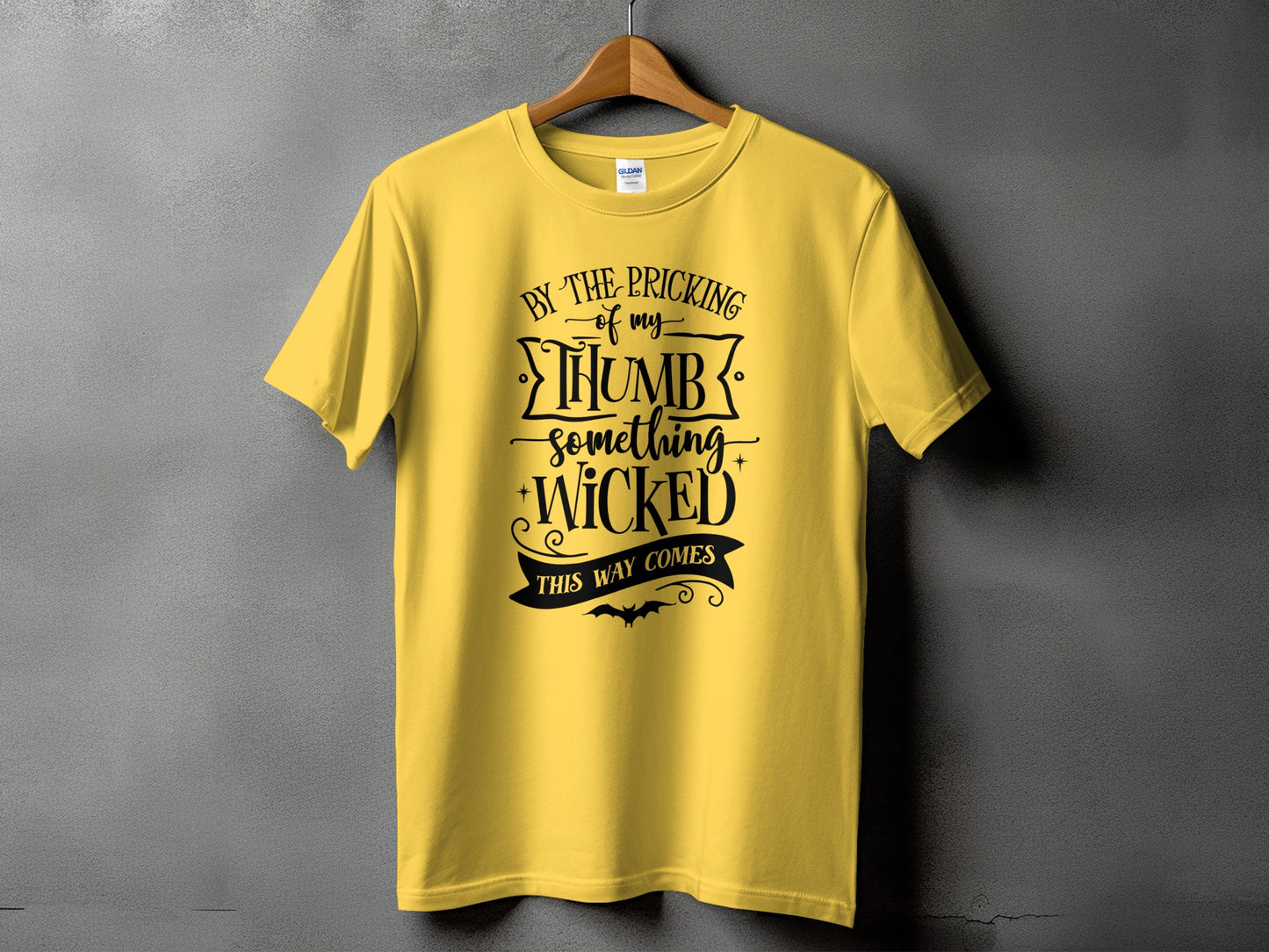 Yellow t-shirt with black text reading "BY THE PRICKING of my THUMB something WICKED THIS WAY COMES"