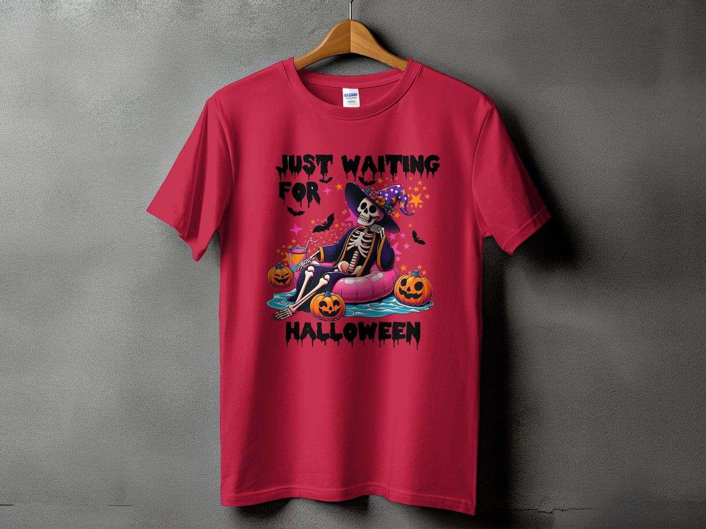 Skeleton floating on an inflatable ring with pumpkins and the text "Just Waiting For Halloween".