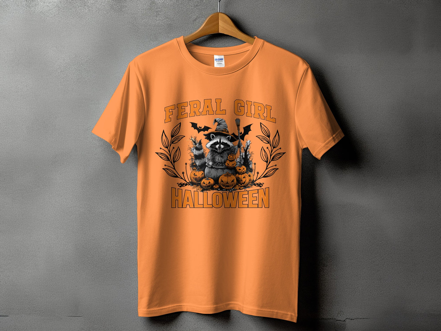 Orange t-shirt with raccoon, pumpkins, bats, and text "Feral Girl Halloween".