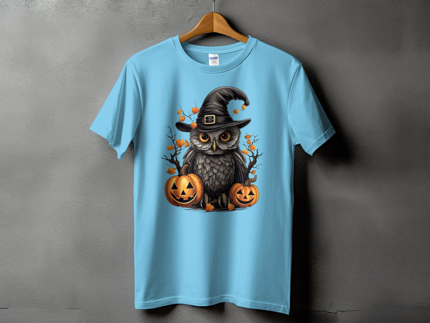 Light blue t-shirt with a Halloween owl wearing a witch hat and surrounded by pumpkins.