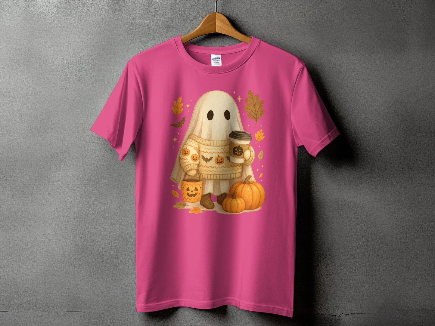Pink t-shirt with a cartoon ghost holding coffee, surrounded by pumpkins and fall leaves.