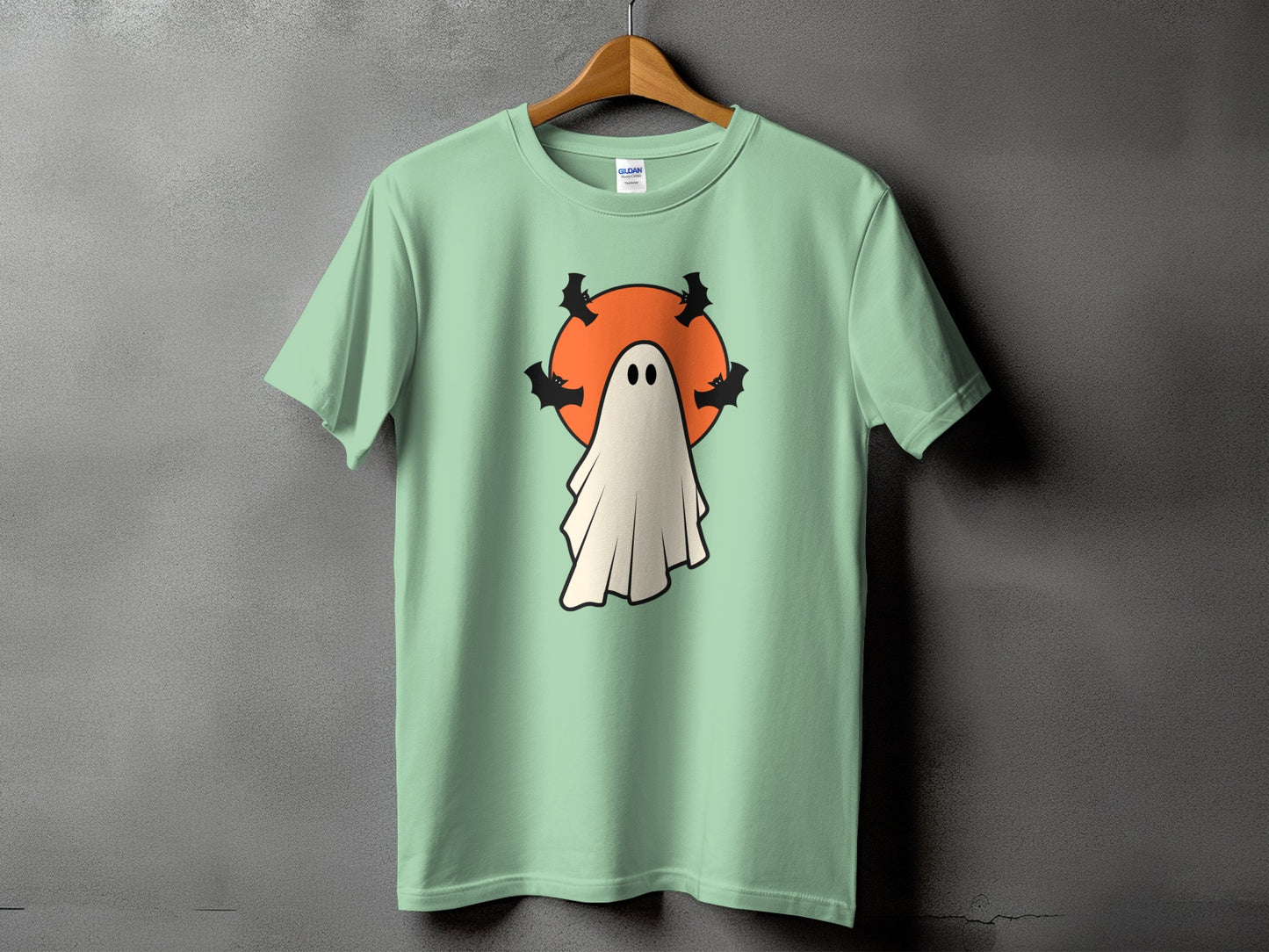 Light green t-shirt with a ghost and bats graphic on a black and orange circle.