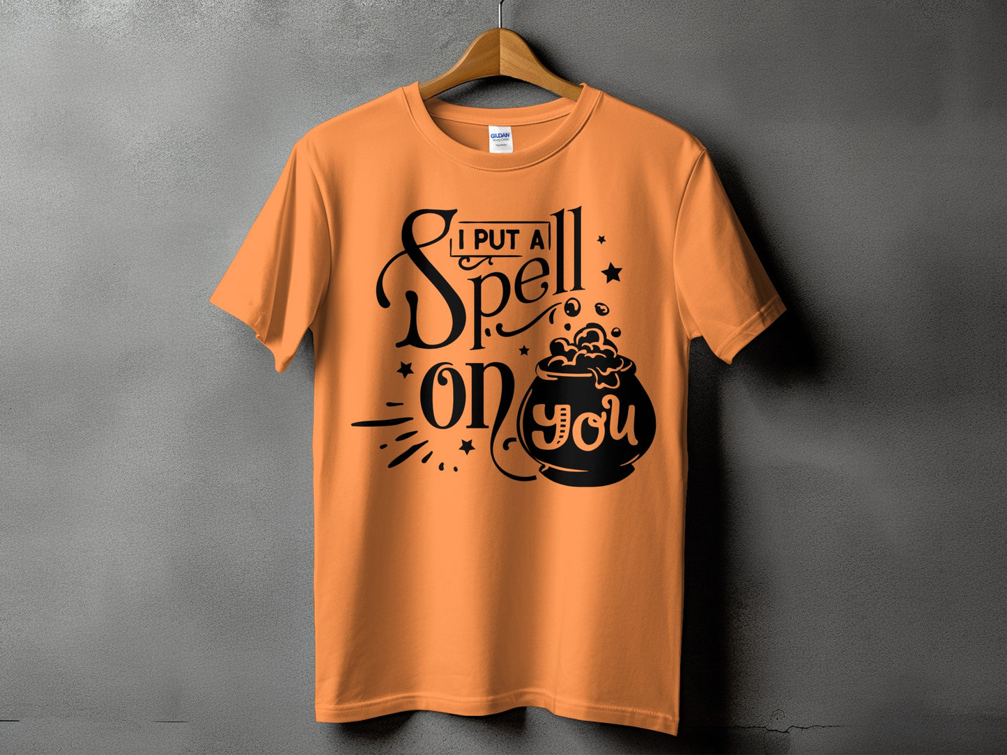 Orange t-shirt with black text and cauldron graphic reading "I PUT A Spell ON YOU".