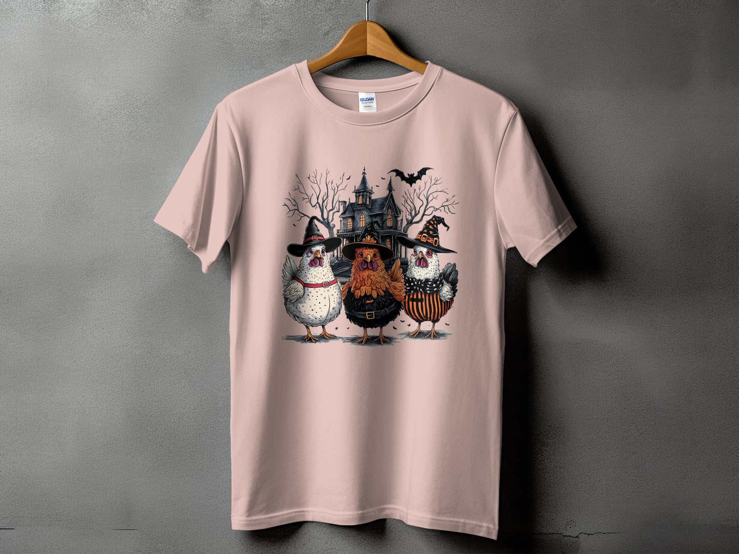 Three chickens in witch hats in front of a spooky house with a bat.