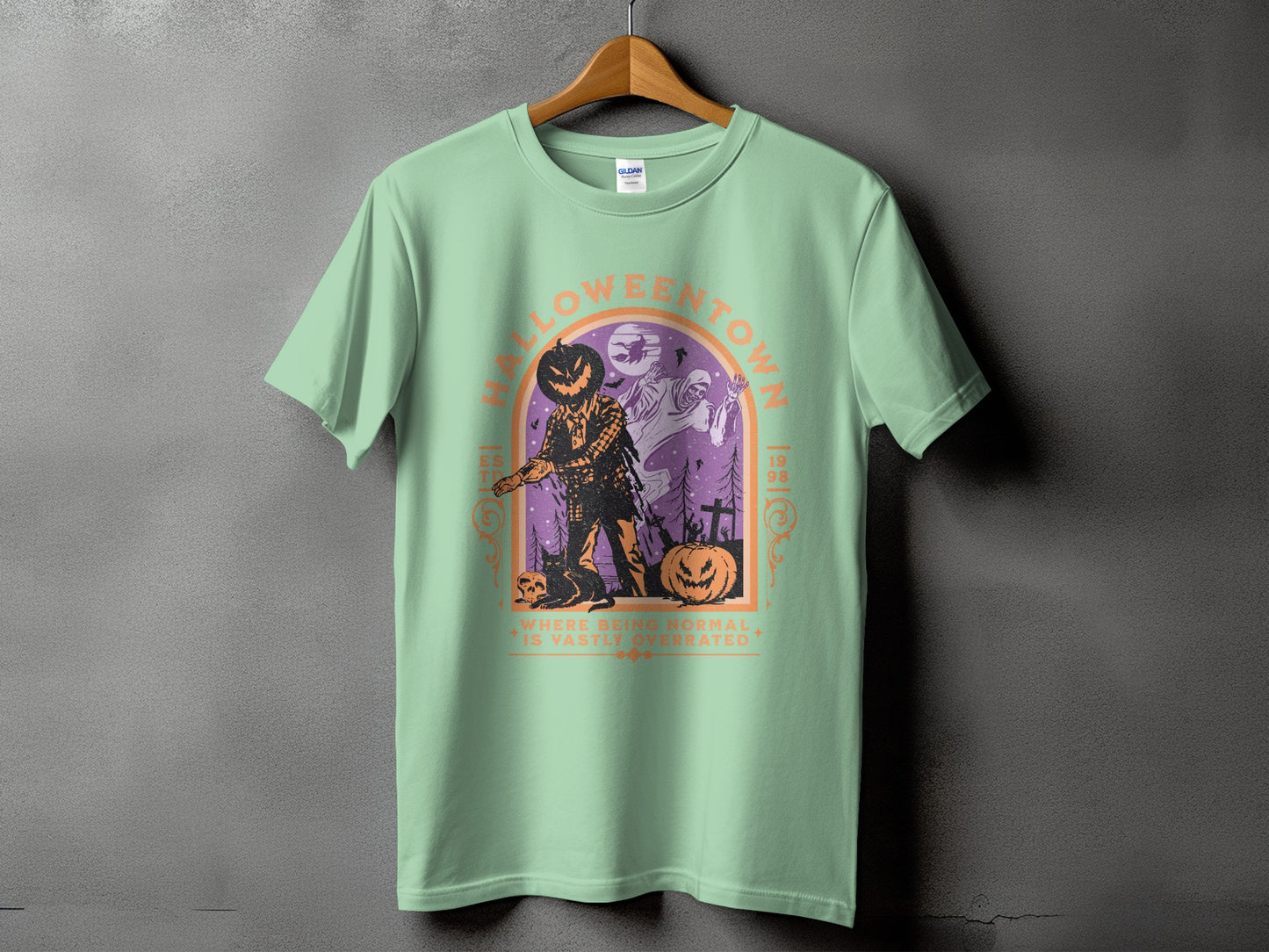 Pale green t-shirt with Halloween Town graphic featuring scarecrow, ghosts, and pumpkins.