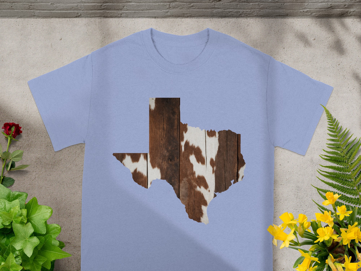 Light purple t-shirt with a Texas shape filled with cowhide and wood grain patterns.